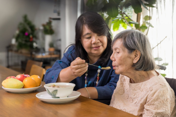 Old woman being assited while eating