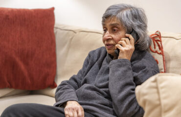 Old elderly, British Asian woman talking on a phone, self isolating during coronavirus outbreak lockdown in UK